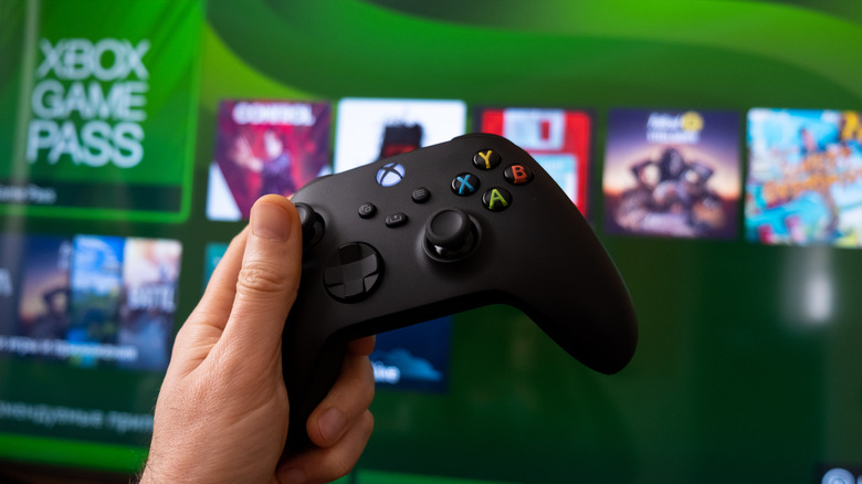 person holding a controller in front of a Xbox Game Pass screen