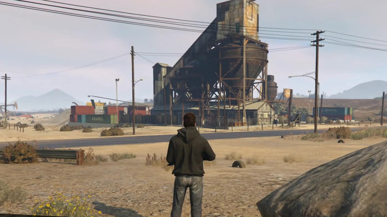 Armed player looking at buildings on desert road