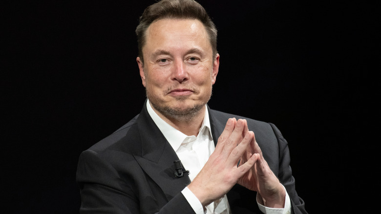 Elon Musk folds his hands during a talkback