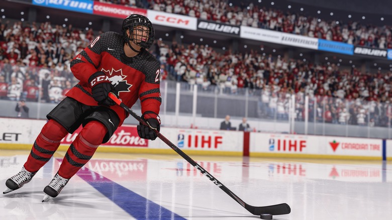 A screenshot from NHL 23 showing a full-body image of a character on the ice, holding a hockey stick and wearing a red strip.