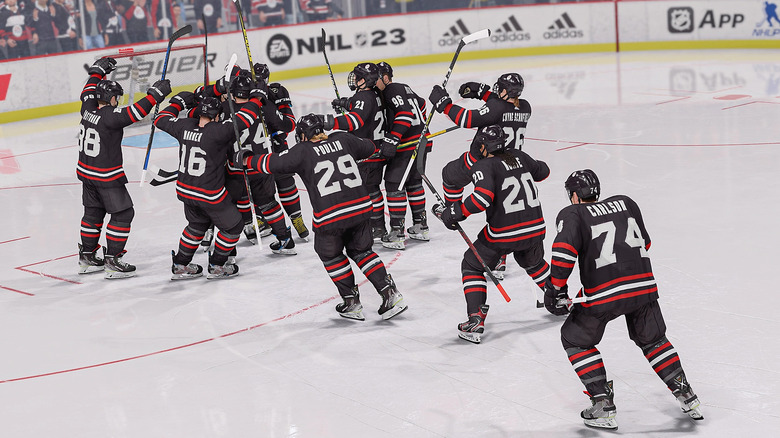 A screenshot from NHL 23 showing a team, wearing black, white and red strips, celebrating.