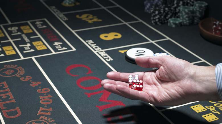 man with dice in hands on poker table