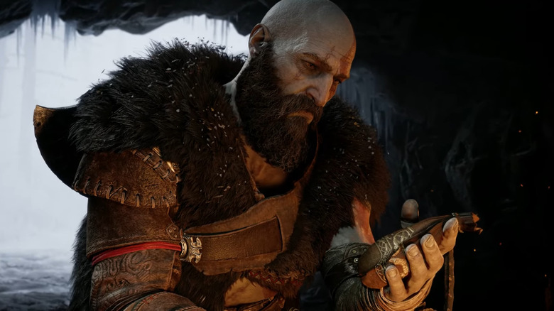 Kratos sitting beside the fire with bag in his hand