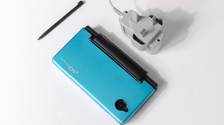 Nintendo DSi with blue case next to stylus and charger