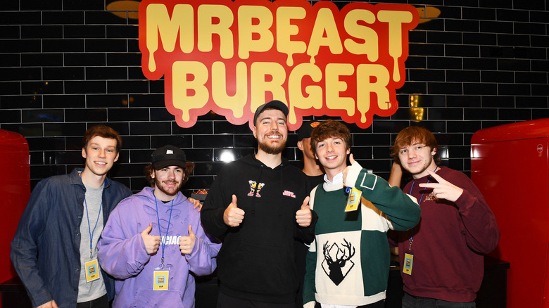 MrBeast and others in front of a MrBeast Burger sign