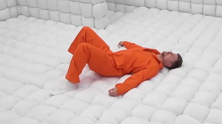 MrBeast laying on ground in orange jumpsuit