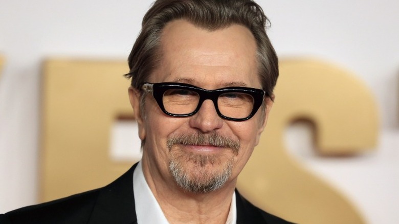 Gary Oldman wearing glasses and smiling