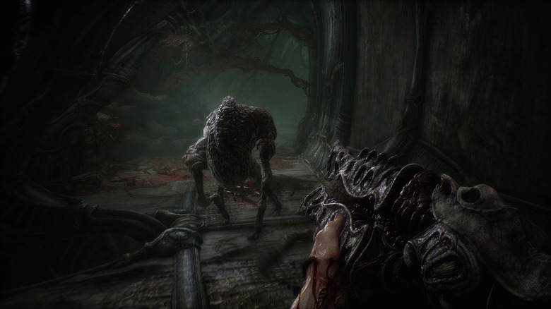 The player character of Scorn aims a fleshy gun at a horror