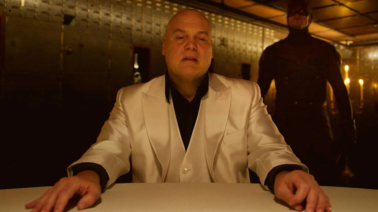 Kingpin sitting table Daredevil standing behind