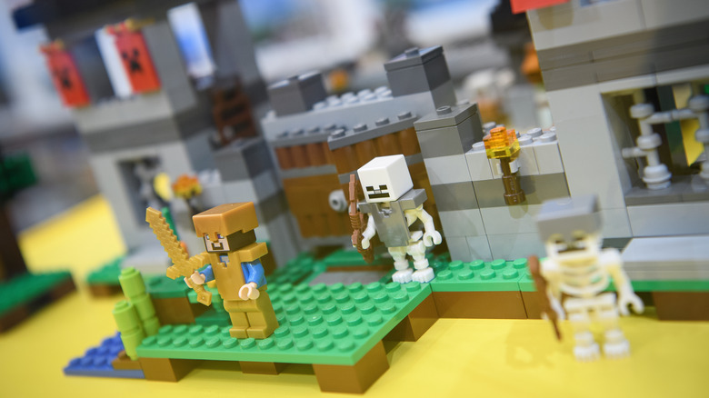 LEGO Minecraft skeletons pose on a desk behind a knight