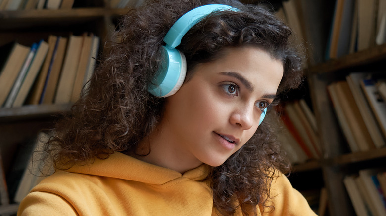 Girl with Brown Skin and Curly Hair wearing light blue wireless headphones